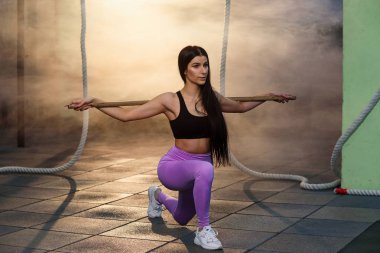 Spor genç kadın spor salonunda halter ile çömelme yapıyor.