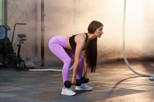 Joven mujer en forma haciendo ejercicio con pesas en el gimnasio . — Foto de Stock