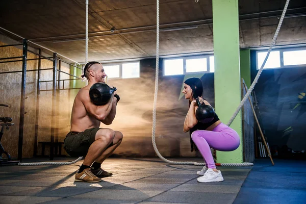 Atractiva pareja joven en ropa deportiva haciendo ejercicio en el gimnasio . — Foto de Stock