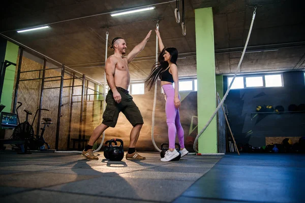 Mujer y hombre guapos en forma que se dan cinco de altura después de un duro entrenamiento exitoso en el gimnasio . — Foto de Stock