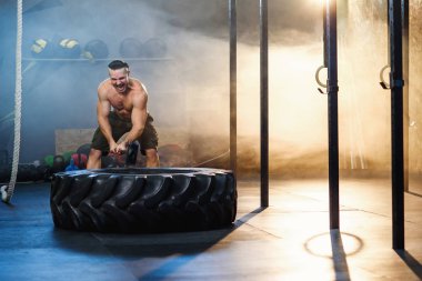 Spor salonunda çekiç kullanarak tekerlek lastik isabet Güçlü genç adam.
