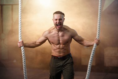 Crossfit halat ile egzersiz yaparken güçlü genç adam çığlık.