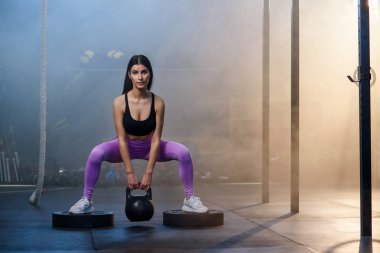 Spor salonunda dumbbells ile egzersiz yapan genç fit kadın.