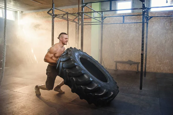 年轻的强壮男人在健身房里翻转轮胎. — 图库照片