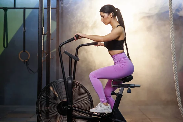 Ajuste atractiva mujer haciendo ejercicio en la bicicleta estática en el gimnasio . — Foto de Stock