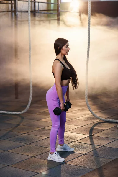 Jovem apto mulher fazendo exercício com halteres no ginásio . — Fotografia de Stock