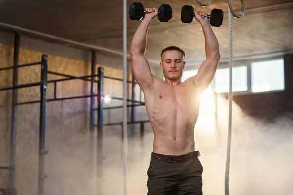 在健身房训练时，年轻的强壮男人用哑铃做俯卧撑. — 图库照片