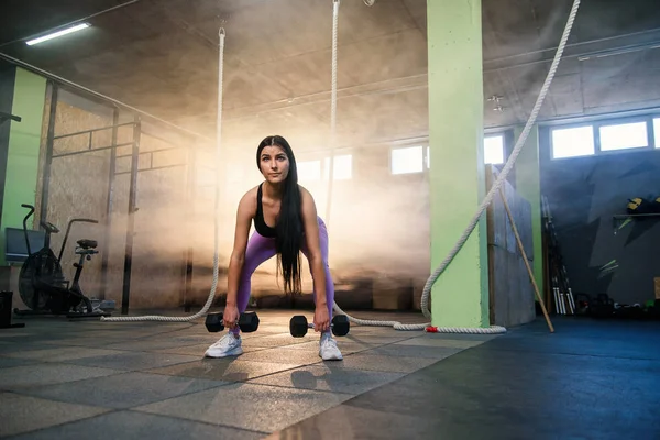 Joven mujer en forma haciendo ejercicio con pesas en el gimnasio . — Foto de Stock