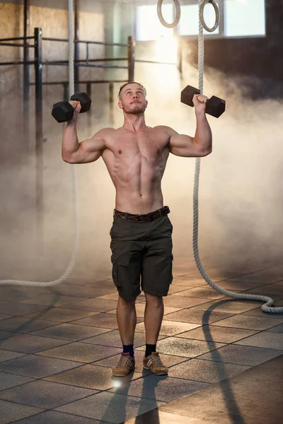 ジムでのトレーニング中にダンベルで腕立て伏せをする若い強い男. — ストック写真