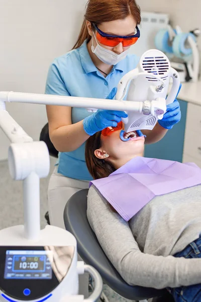 Teeth whitening procedure for pretty happy female patient in a dental clinic