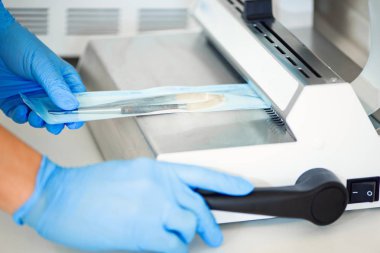 Otoklavda sterilize hazır vakum paketleme makinesi tıbbi aletleri ile paketlenmiş tutan Diş hekimi asistanları eller. Diş ofisi. Seçici odaklama, metin için alan.
