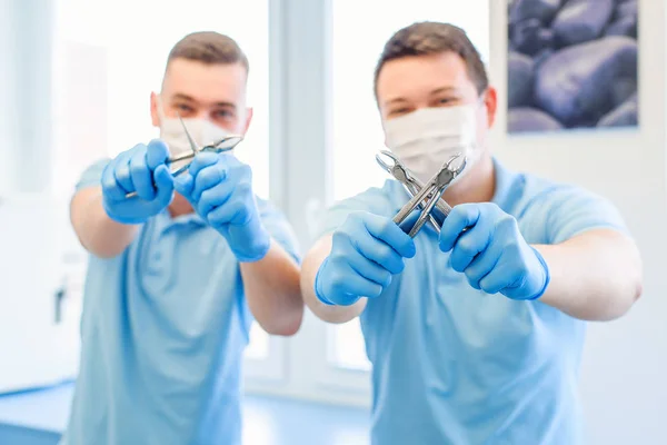 Two male doctors with dental instruments in the hands. Teeth care concept.