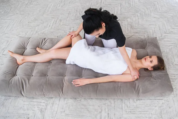 Молода жінка отримує традиційний тайський масаж розтяжки від терапевта ізольовані на білому тлі — стокове фото