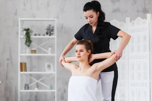 Dolly shot of female therapist stretching hands and shoulder of young sport woman in clinic. — Stock Photo, Image