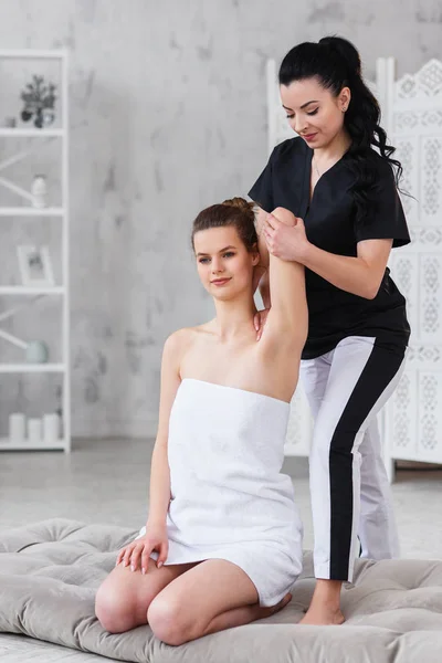 Young attractive woman on treatment procedure while female therapist streching hands of patint. Dolly shot. — Stock Photo, Image