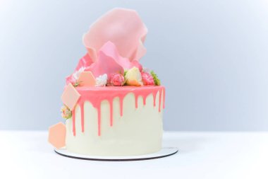 Beyaz ahşap arka planda siyah tepsi üzerinde kalan şık renkli kek Dekoratif unsurları. Doğum günü partisi kutlama hediyesi.