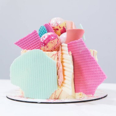 Beyaz ahşap arka planda siyah tepsi üzerinde kalan şık renkli kek Dekoratif unsurları. Doğum günü partisi kutlama hediyesi.