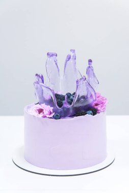 Beyaz arka planda beyaz tepsi üzerinde kalan dekoratif menekşe renkli kek. Tatil pastasında karamel sıçrama. Doğum günü partisi kutlama hediyesi.
