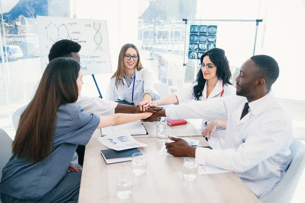 Profesyonel genç doktorlar uluslararası grup ellerini çırparak ve modern bir klinikte bir tıp konferansında gülümseyerek vardır. Tıp ve sağlık kavramı.