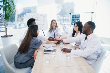 Profesyonel genç doktorlar uluslararası grup ellerini çırparak ve modern bir klinikte bir tıp konferansında gülümseyerek vardır. Tıp ve sağlık kavramı.