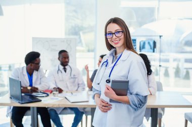 Kadın doktor hastane konferans odasında tablet bilgisayar kullanır. Klinikte toplantı odasında beyaz tıbbi üniforma profesyonel kadın doktor.