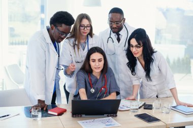 Çok ulusal doktor analiz konferans odasında tartışıldığı dizüstü kullanarak grup. Yan görünüm.