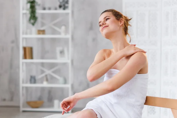 Cute caucasian woman applies natural moisturizer cream on gentle smooth skin after on the white spa salon background. — Stock Photo, Image