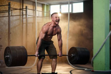 Spor genç adam spor salonunda halter ile çömelme yapıyor.