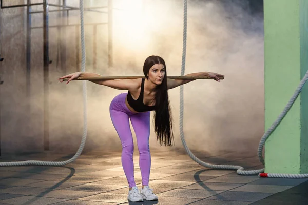 Hermosa mujer joven en uniforme deportivo haciendo ejercicios de cardio en cuclillas durante el entrenamiento en el gimnasio . — Foto de Stock
