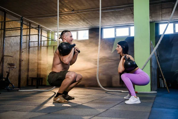 Atractiva pareja joven en ropa deportiva haciendo ejercicio en el gimnasio . — Foto de Stock