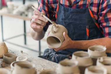 Çömlekçilik çalışmaları sırasında odaklanmış orta yaş adam.