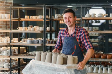 Beyaz erkek çömlekçi çömlek seramik kapları ile tepsi tutan.