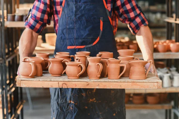 Macho manos de alfarero sosteniendo bandeja con ollas de cerámica al horno en la cerámica . —  Fotos de Stock