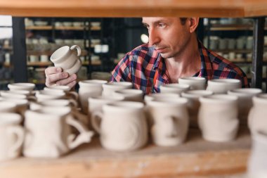 Çömlekçilikte el yapımı kap arayan odaklanmış adam.