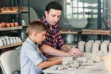 Büyük yaratıcı çömlek atölyesinde seramik kaplar ile birlikte küçük kardeşi ile orta yaş adam yan görünümü.