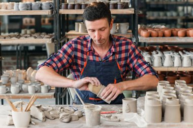 Büyük bir yaratıcı çömlek atölyesinde nemli bir sünger bir fincan kil şeklinde bir iş üniforması mendil orta yaşlı bir adam.