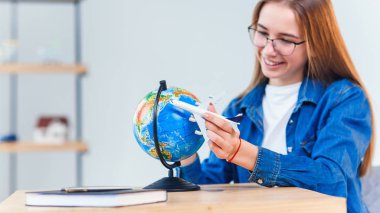 Genç gülümseyen kadın elinde uçak modeli tutar. Mutlu güzel kız tatil gezisi planlama.