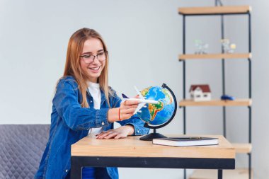 Tatilin hayalini kurangüzel bir kadın. Kız elinde uçak bir model tutar ve küçük bir dünya etrafında uçar.