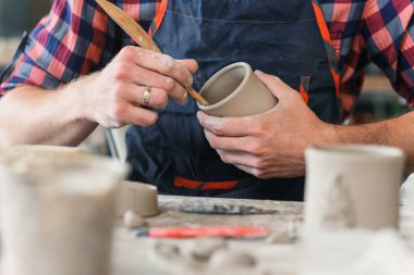 Büyük bir yaratıcı çömlek üretiminde fincan kil şeklinde ahşap yığını ile üniforma lı bir çalışma orta yaşlı bir adam.