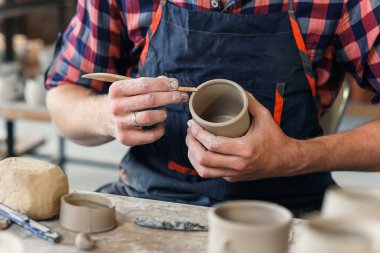 Büyük bir yaratıcı çömlek üretiminde fincan kil şeklinde ahşap yığını ile üniforma lı bir çalışma orta yaşlı bir adam.