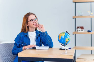 Genç neşeli kadın başının üzerinde bir model küre tutan bir seyahat hayal. Tatil planlama.