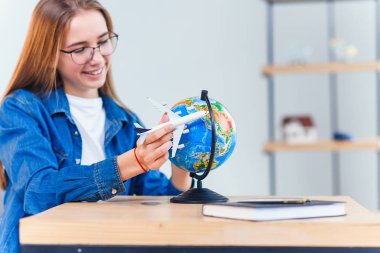 Genç gülümseyen kadın elinde uçak modeli tutar. Mutlu güzel kız tatil gezisi planlama.