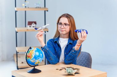 Kız elinde uçak ve araba modelleri tutar ve yolculuk için en iyi ulaşım seçerek. Renkli hayatınız için dünyayı dolaşın.