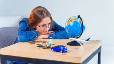 Üzgün kız, tasarruflarını ve seyahatler ve kendi araçları yla ilgili hayallerini sayar. Tasarruf parası kavramı.