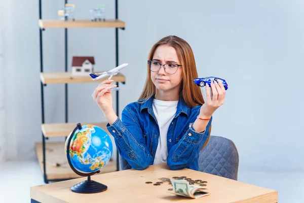 Kız elinde uçak ve araba modelleri tutar ve yolculuk için en iyi ulaşım seçerek. Renkli hayatınız için dünyayı dolaşın.