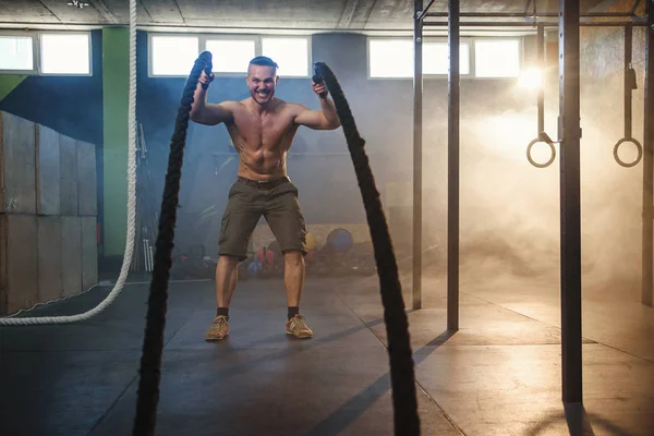 Красивий сильний чоловік робить вправи для м'язів з бойовими мотузками у фітнес-центрі . — стокове фото