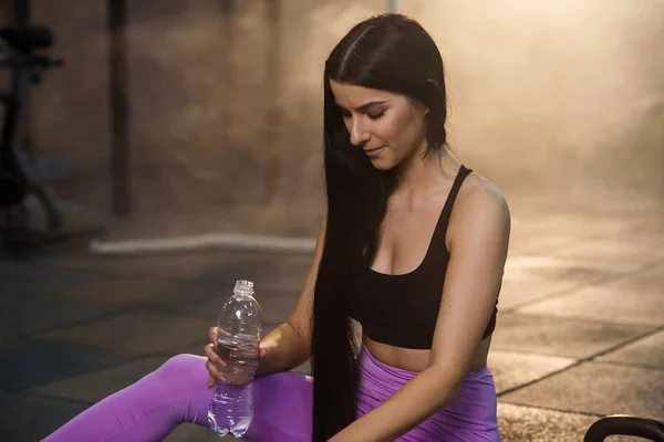 Güzel uygun kadın spor salonunda egzersiz sonra plastik şişe biraz su içme. — Stok fotoğraf
