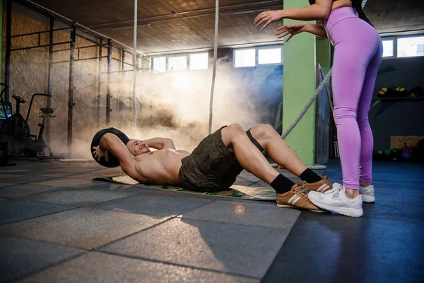 Ajuste homem caucasiano fazendo exercício de bola abdominal com personal trainer no ginásio . — Fotografia de Stock