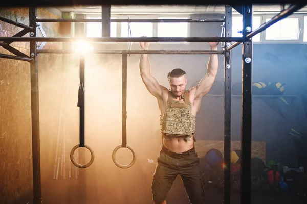 Homem fitness atraente fazendo pull-ups na barra transversal durante o treinamento no ginásio moderno. Fechar tiro . — Fotografia de Stock