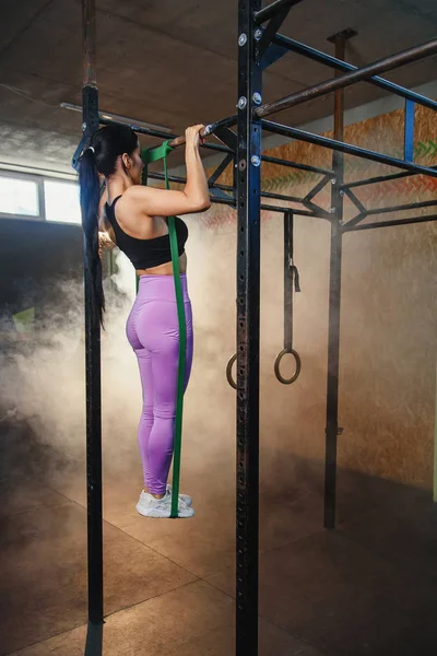 Fuerte mujer en forma haciendo tire hacia arriba en la barra horizontal . — Foto de Stock